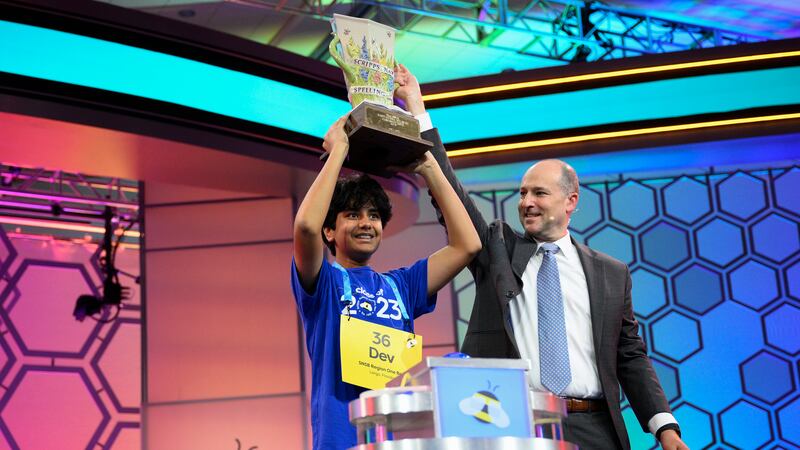 Dev Shah, 14, from Largo, Fla., lifts the trophy next to Scripps CEO Adam Symson after he won...